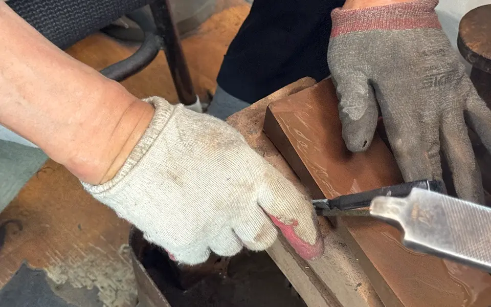 An artisan’s gloved hands sharpening a blade at the tailor’s shears stall