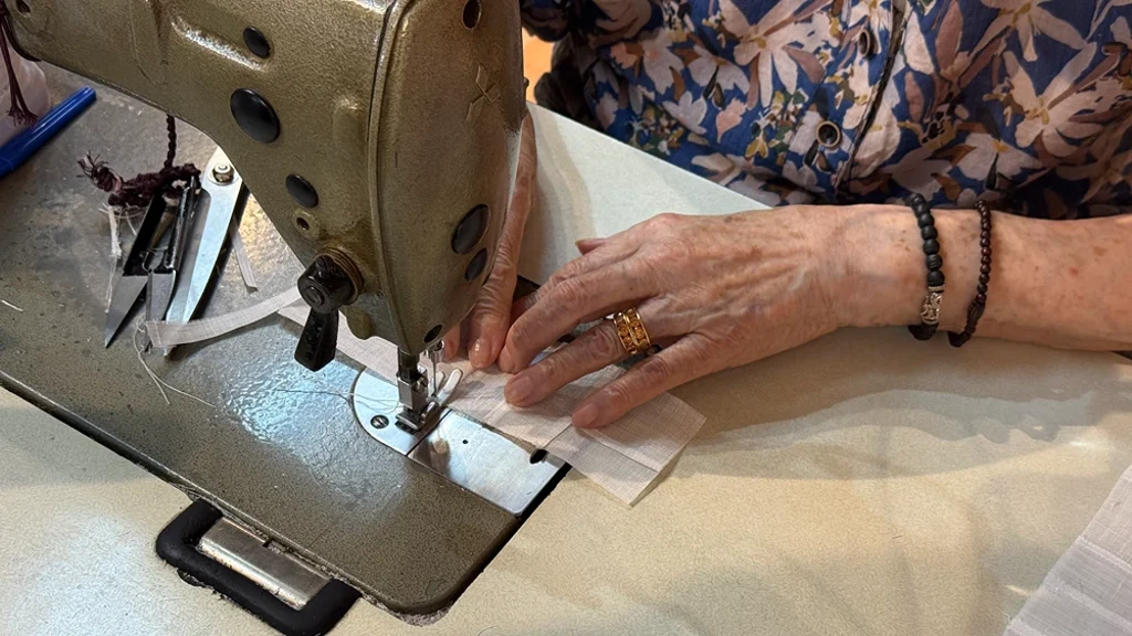 An artisan’s hands guiding fabric through a sewing machine